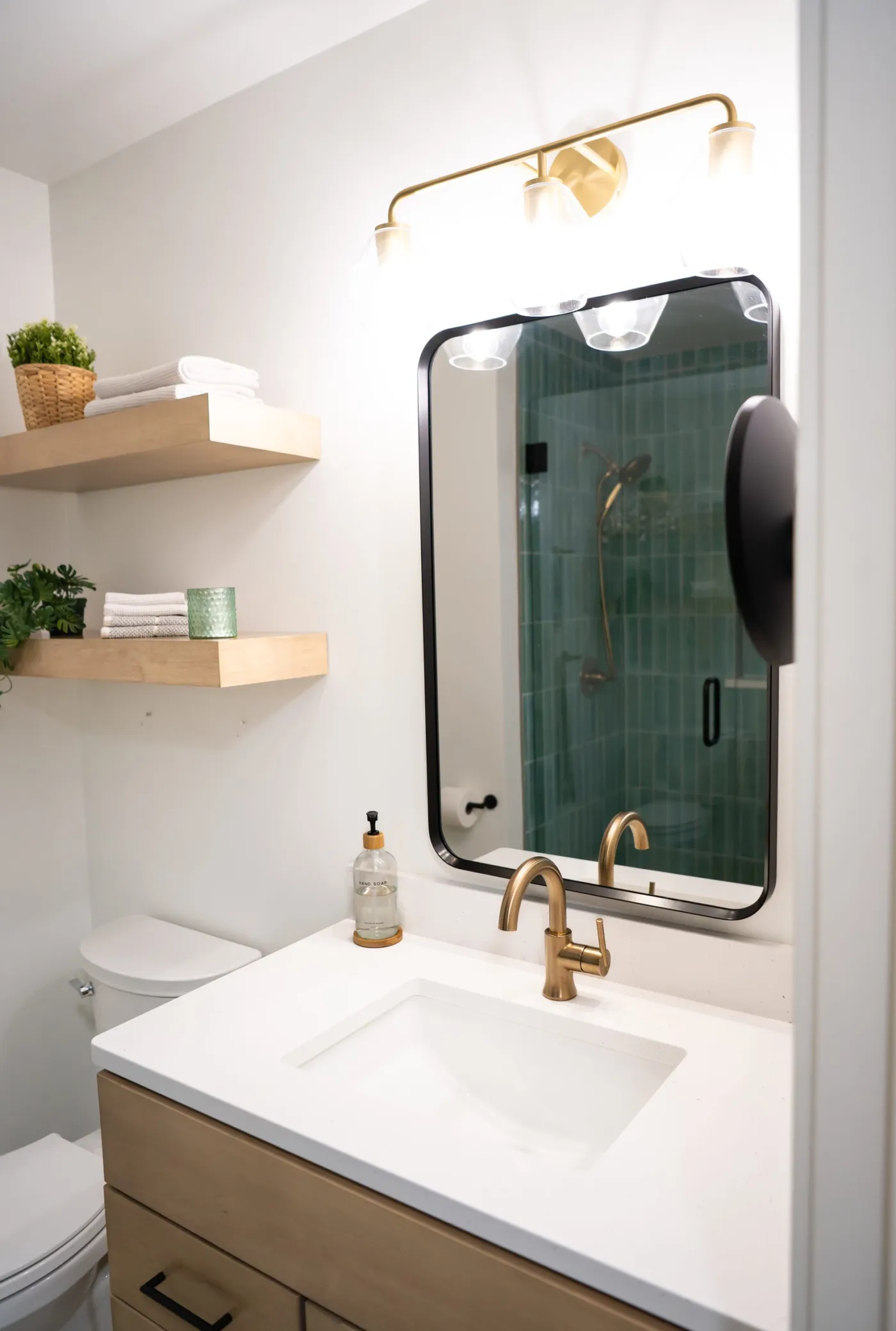Bathroom vanity with an arched mirror, brass faucet and floating shelves