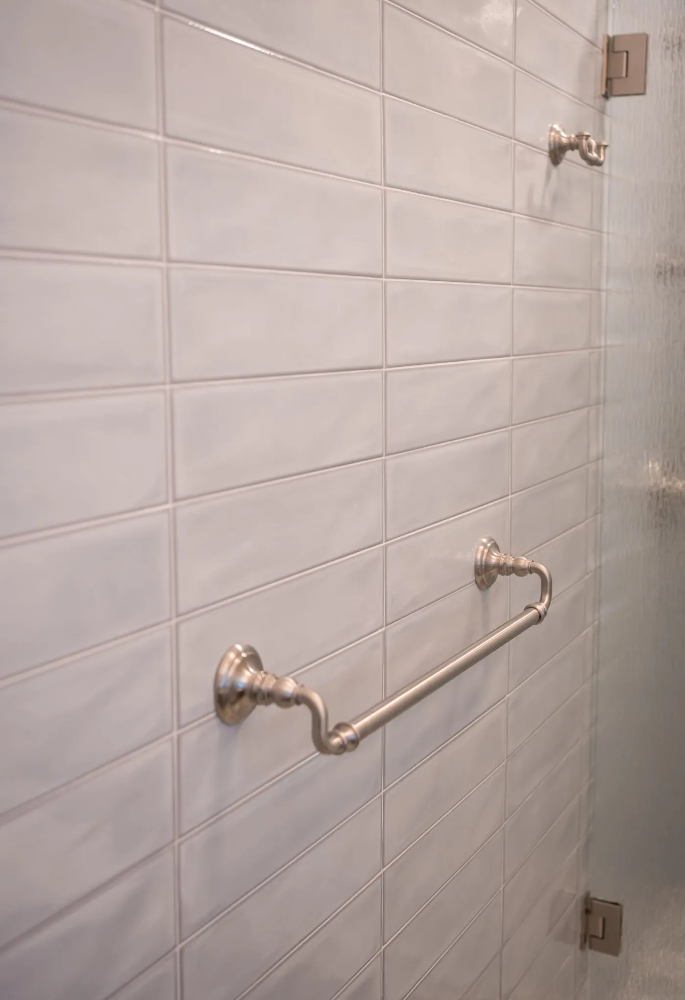 Brushed nickel towel bar mounted on a tiled wall