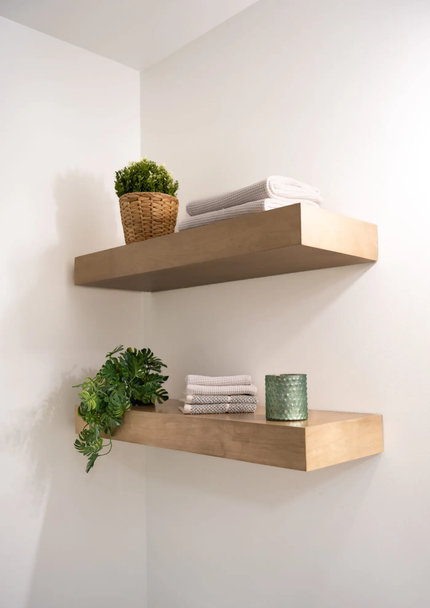 Floating white oak shelves used for towel storage in a remodeled bathroom