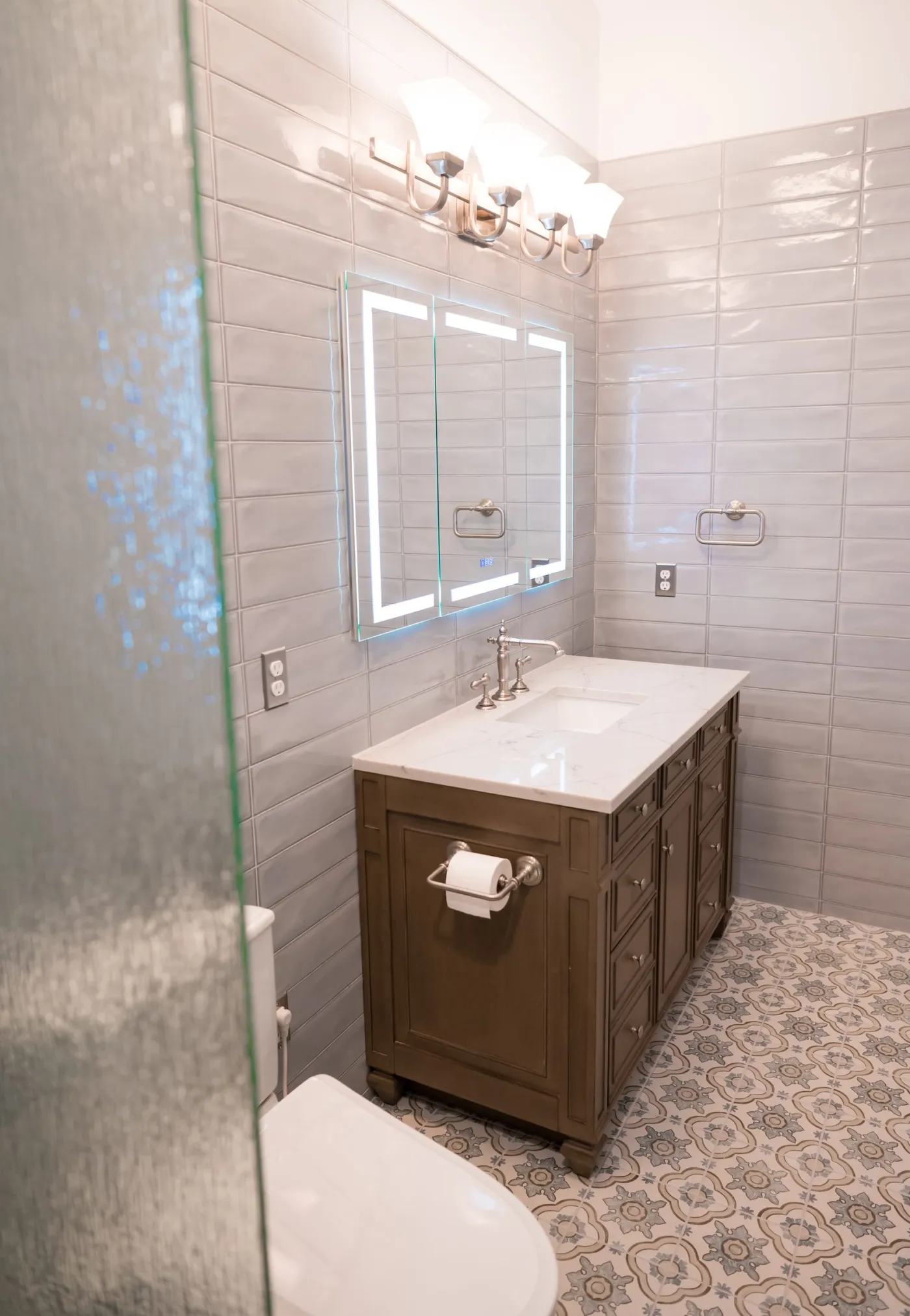 Gray tile carried floor to ceiling on every wall of a remodeled bathroom