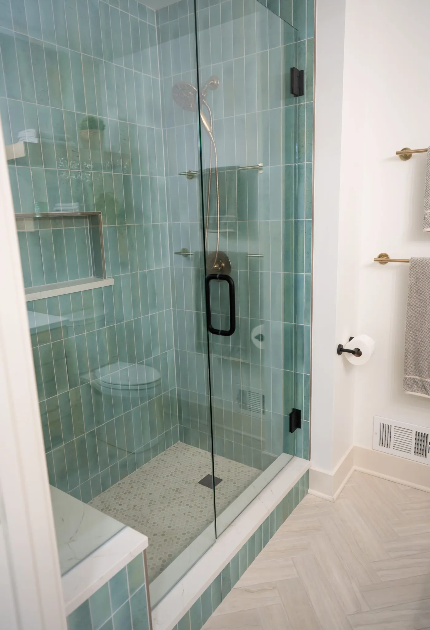 Frameless glass walk-in shower with green stacked tile and a built-in bench
