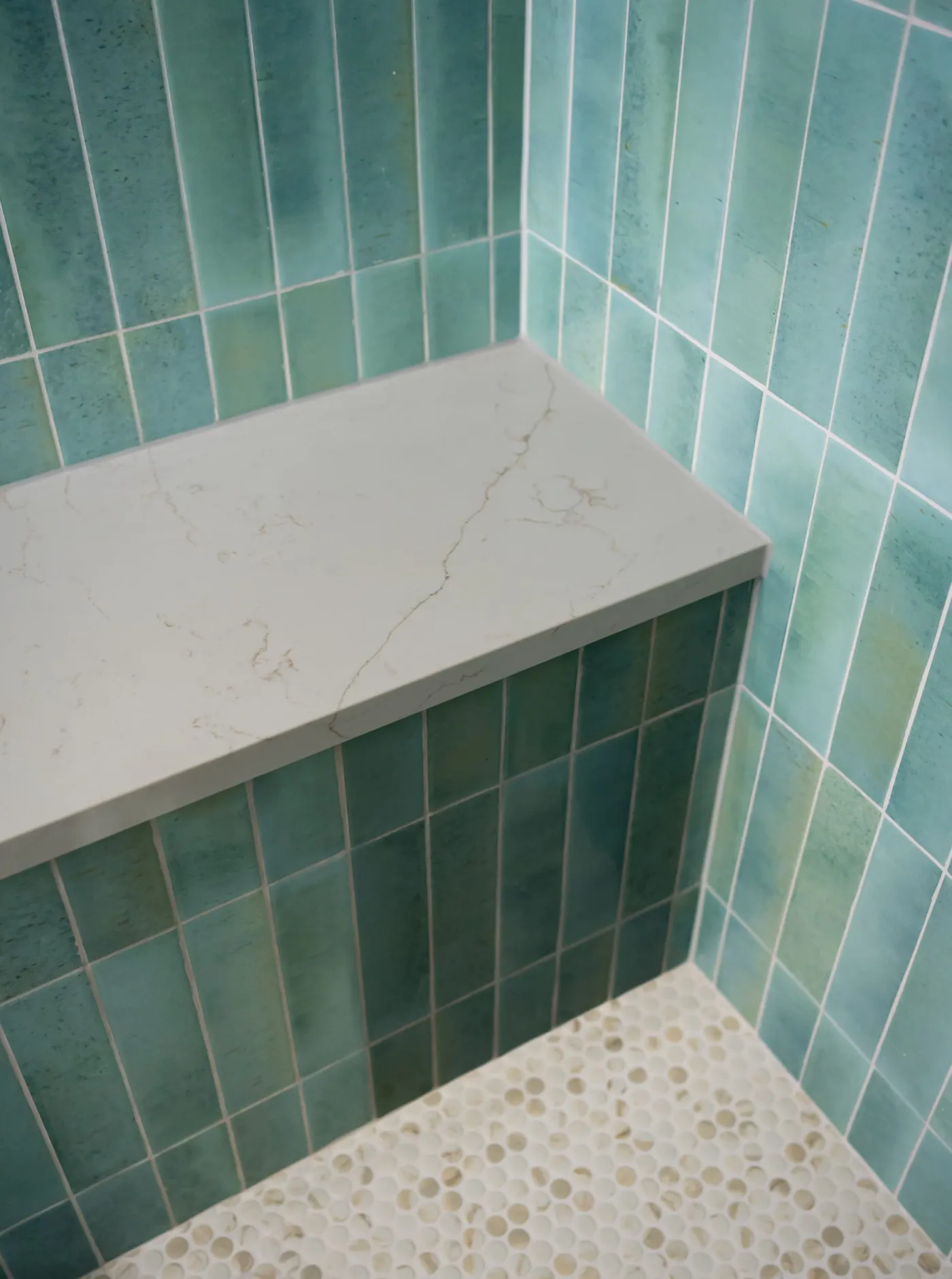 Quartz shower bench built into a green tile shower