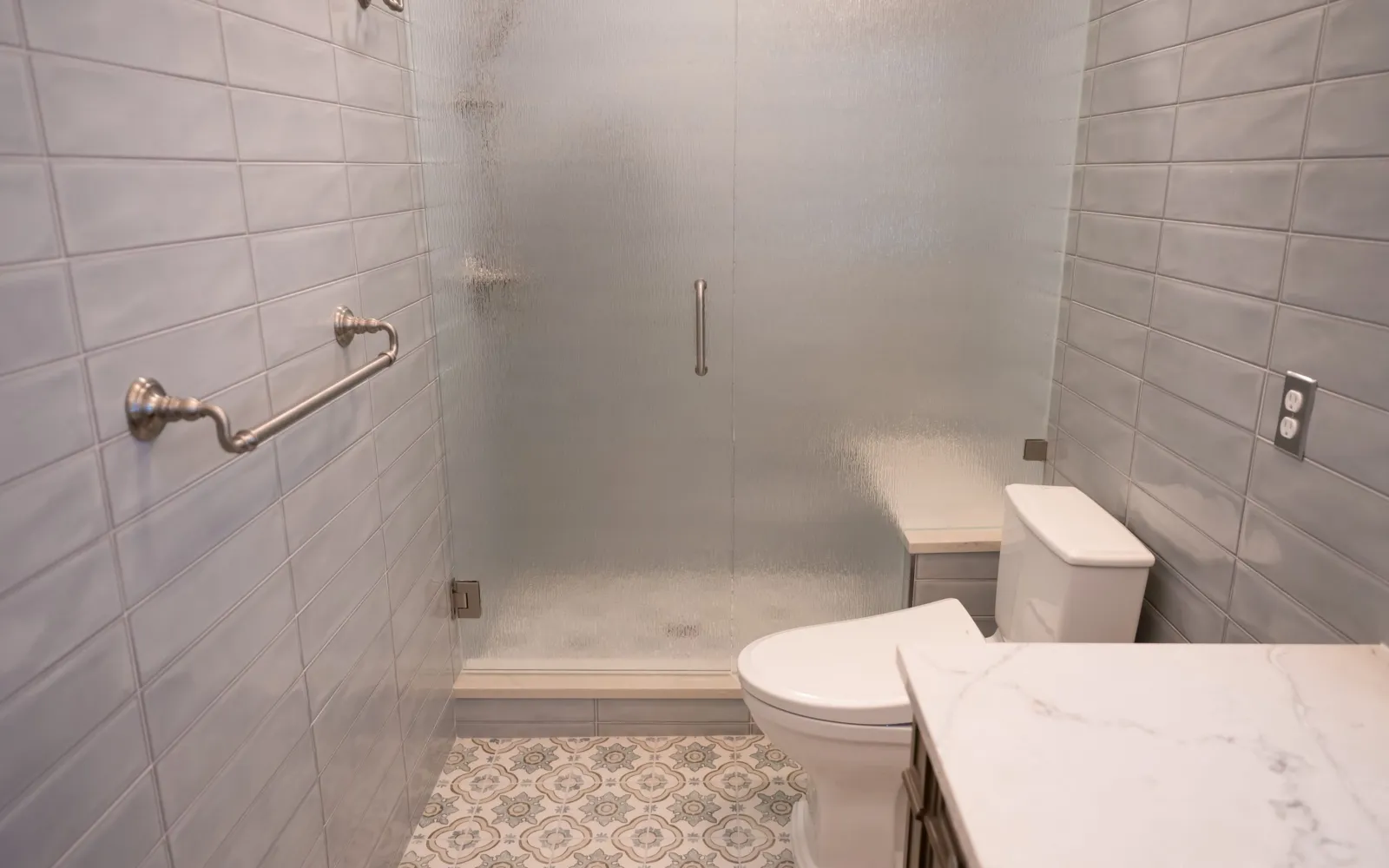 Walk-in tiled shower with a frosted glass door and low threshold