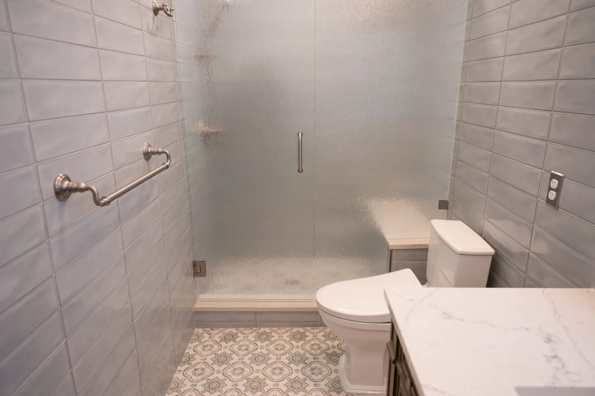 Walk-in tiled shower with a frosted glass door and low threshold